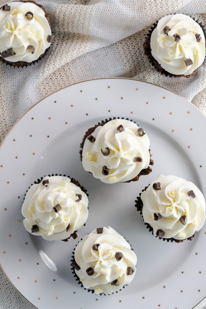 A plate of chocolate cupcakes with American buttercream frosting. 