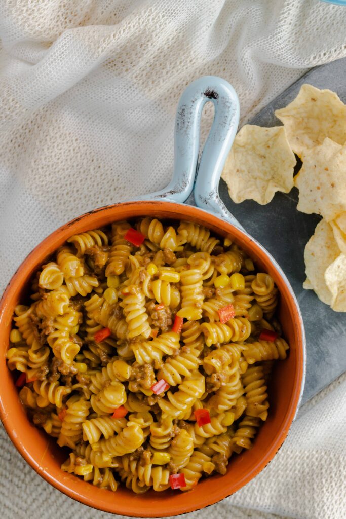 A bowl of taco pasta with a side of tortilla scoops. 