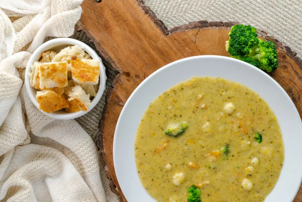 Broccoli and cheddar soup with bread pieces on the side. 