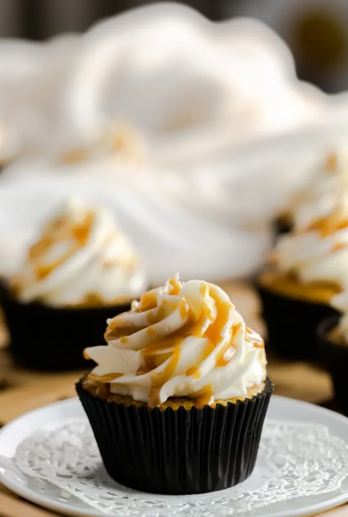 Butterscotch cupcake in a black cupcake wrapper drizzled with homemade butterscotch sauce. 