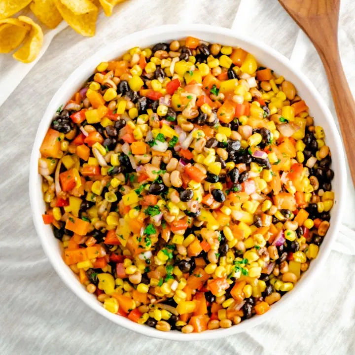 A large bowl of cowboy caviar with a serving spoon.