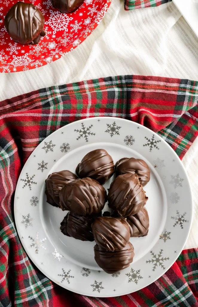 Platter of peanut butter balls sitting on a red and green decorative napkin. 