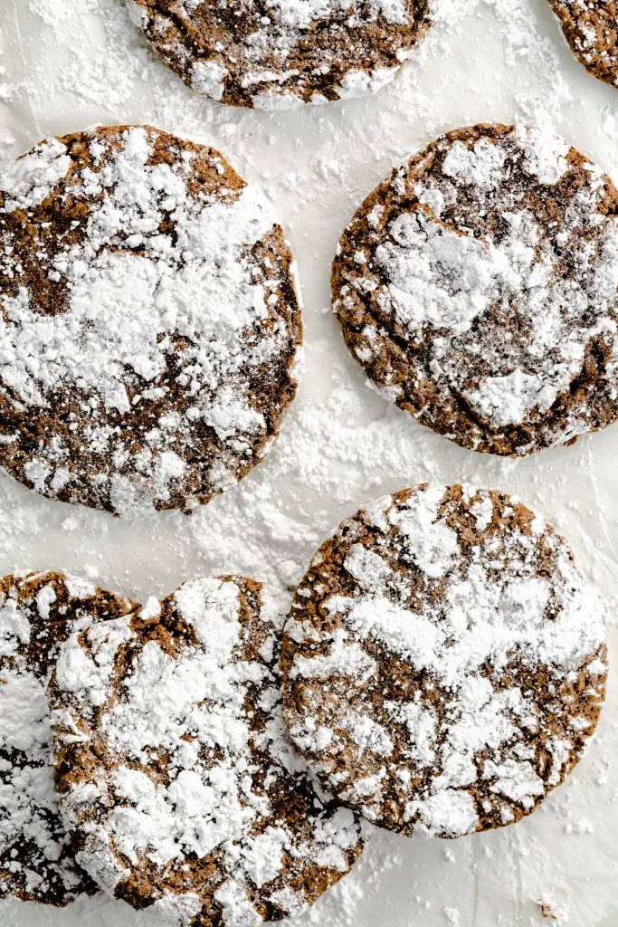 Chocolate crinkle cookies laying on parchment paper. 