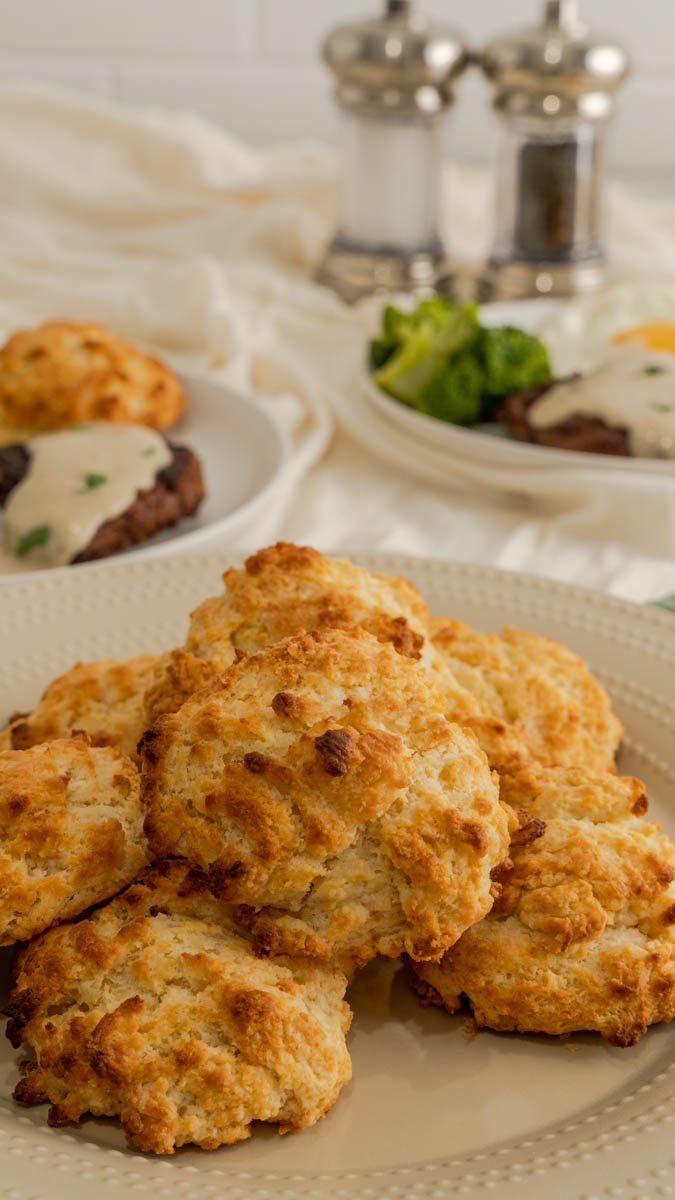 A plate of drop biscuits on a beige plate.