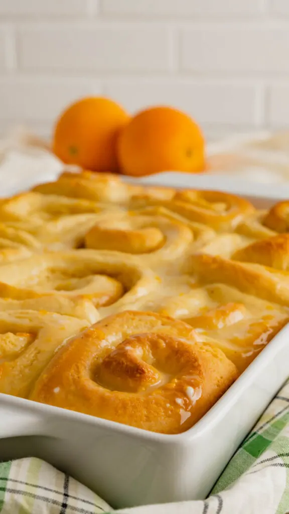 Side view of a white baking dish with freshly baked sweet orange rolls.