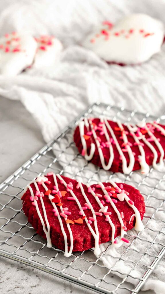 Red Velvet Shortbread Cookie drizzled with white chocolate and Valentine's Day sprinkles.