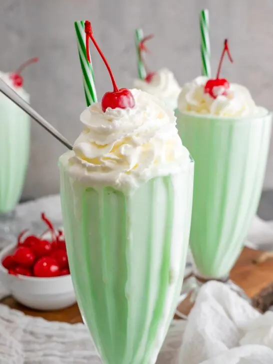 Copycat shamrock shake in a classic milkshake glass with a paper green straw.