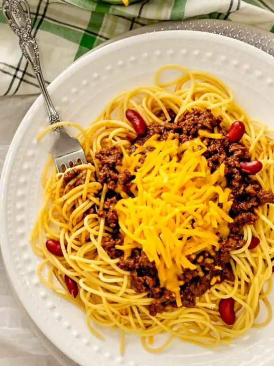 Skyline Chili with spaghetti twirled around a fork on a plate.
