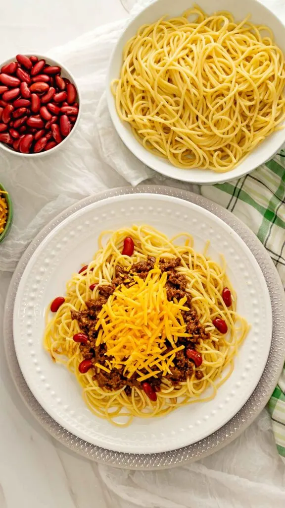 Instant Pot Cincinnati Chili on a plate with pasta, kidney beans, and shredded cheese.