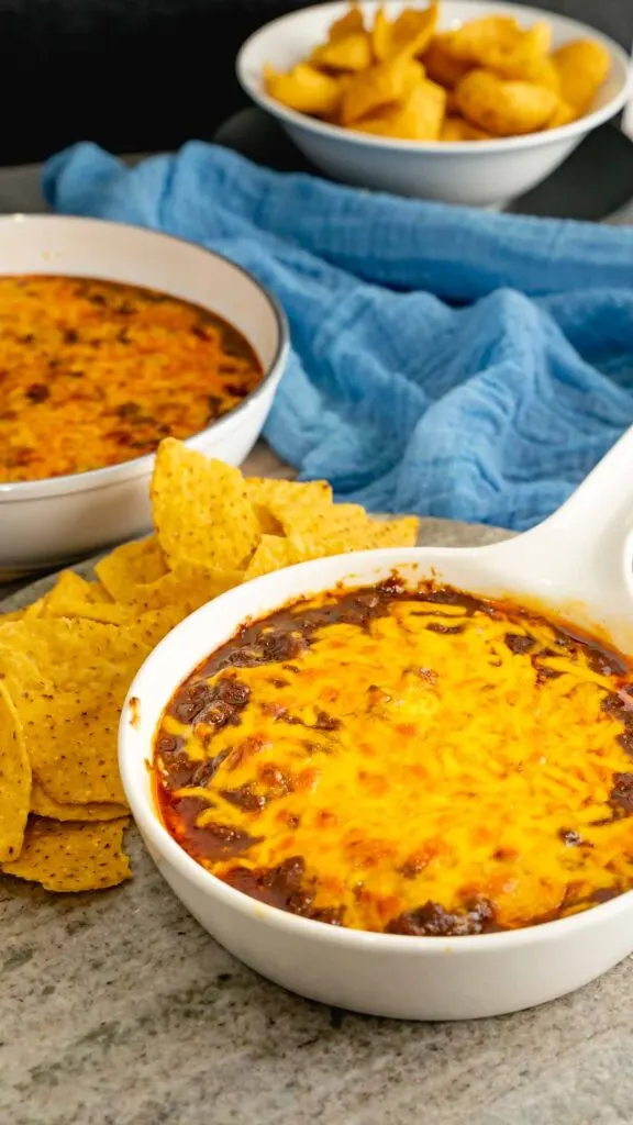 Two dishes of skyline chili dip topped with melted cheese.