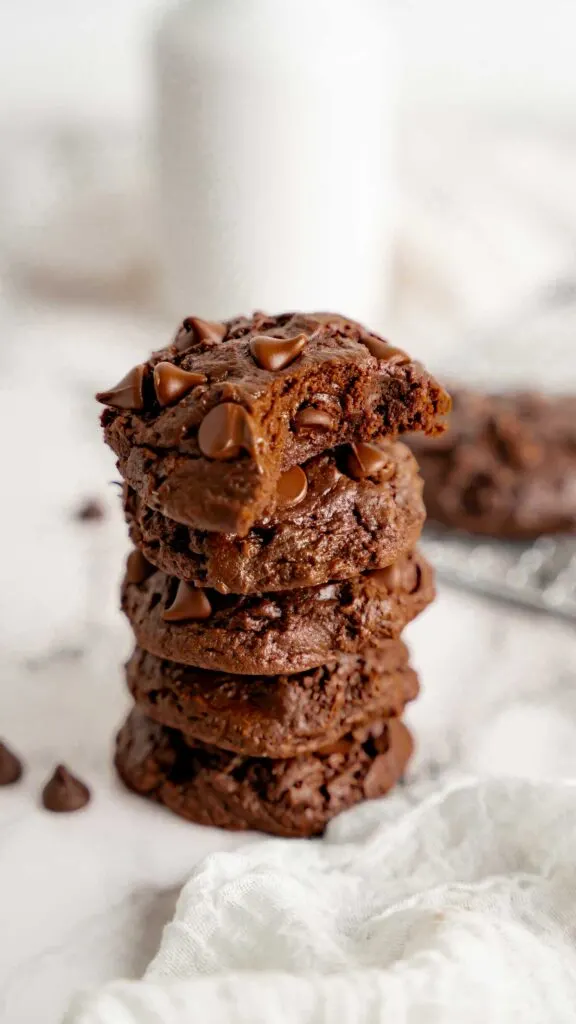 A stack of thick fudge cookies with a bite taken out of the top cookie.