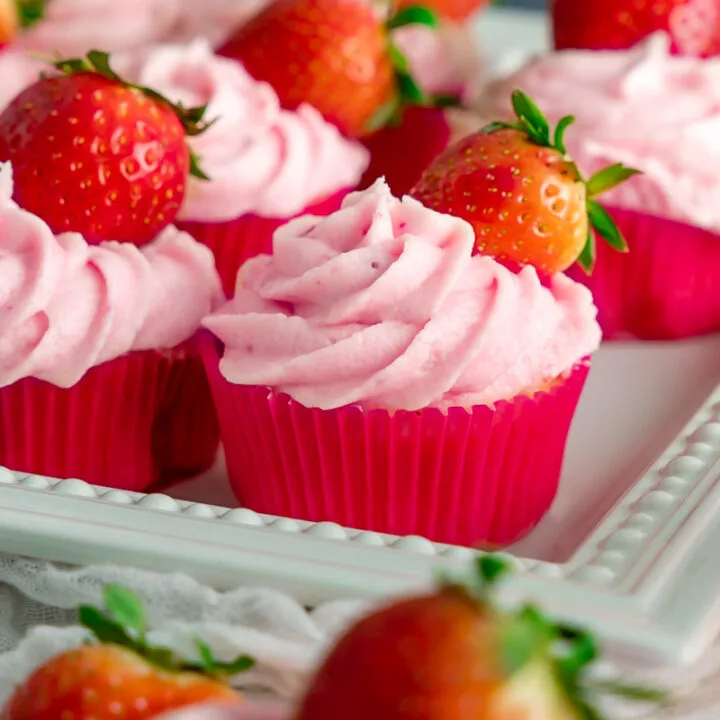 A square platter of strawberry lemon cupcakes topped with fresh strawberries.