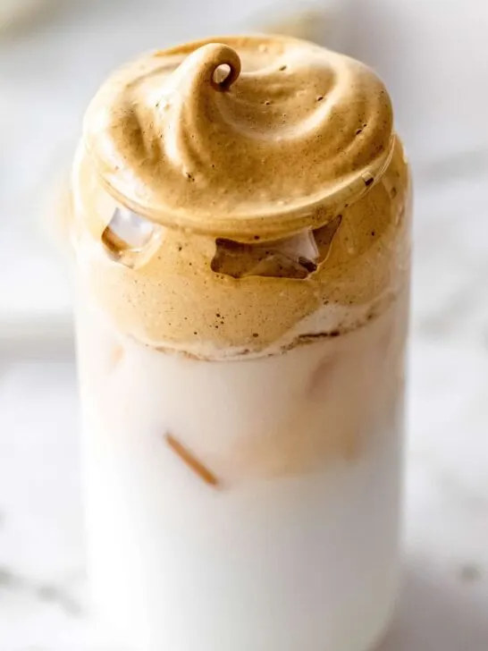 A glass can tumbler filled with an Iced Gingerbread Dalgona Latte inspired by Starbucks.