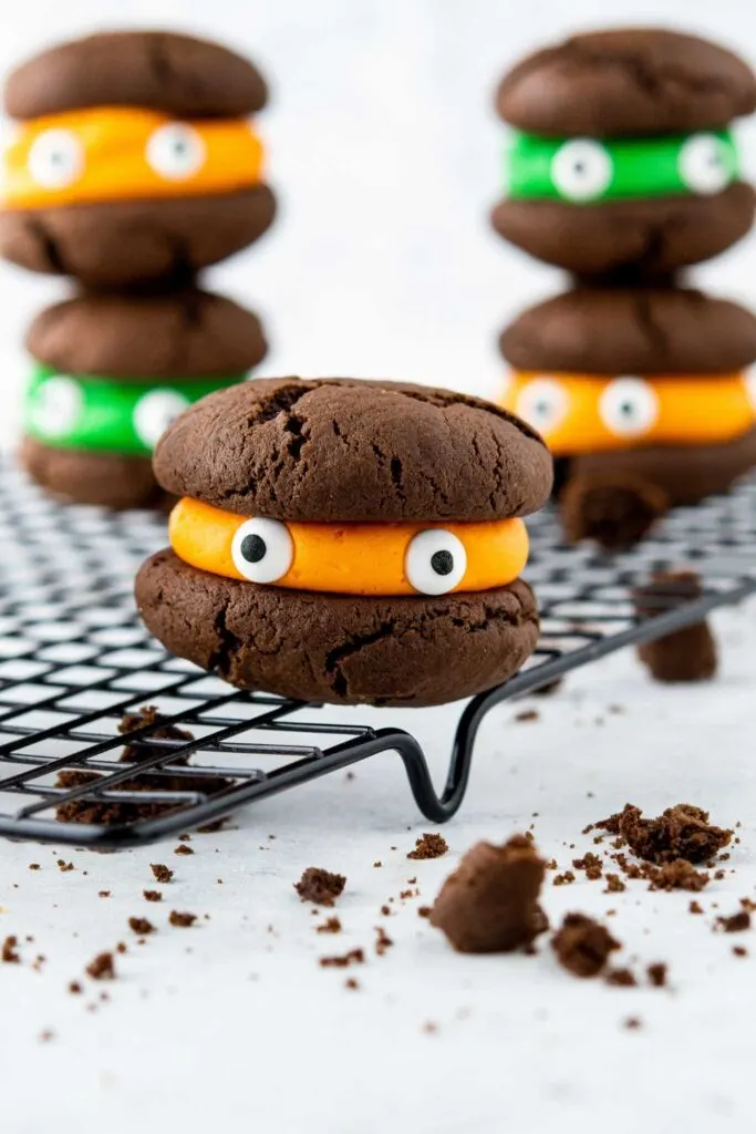 A Halloween Sandwich cookie with orange filling with candy eyes.